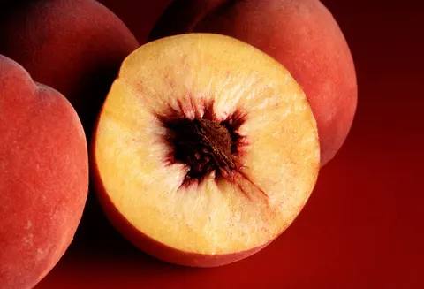 Cut peach showing ripe flesh and pit.